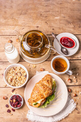Healthy breakfast concept. Morning good mood with tea, croissant, granola, milk, and jam
