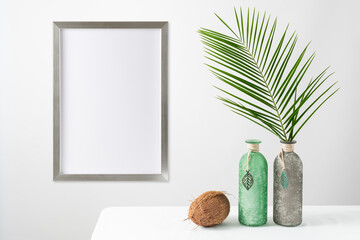 Poster mockup or silver wooden photo frame in modern style on light wall with natural palm leaves...