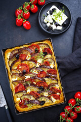 Traditional French Tarte with eggplant, tomato and feta cheese served as top view in backing form