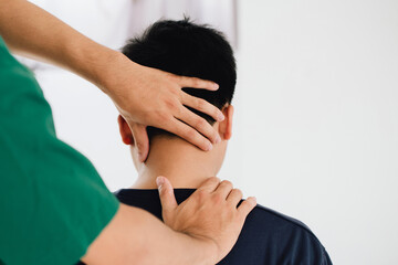 physiotherapist massage therapist holding male client's head and massaging tight neck muscles the...
