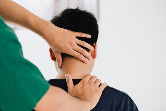 physiotherapist massage therapist holding male client's head and massaging tight neck muscles the result of prolonged use of mobile phones.Office Syndrome