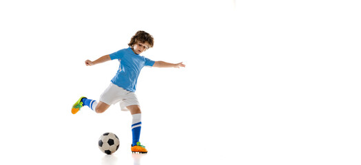 Flyer. Portrait of little male football soccer player, boy training with football ball isolated on white studio background. Concept of sport, game, hobby