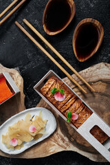 Sushi roll with baked salmon in disposable paper box on wooden cut. Concept delivery service. Japan food in eco container. Zero waste packaging. High quality photo