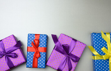 Fototapeta premium many gift boxes tied with a silk ribbon on a gray background, top view. Festive backdrop