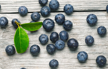 Scattered blueberries on wooden background with leaves