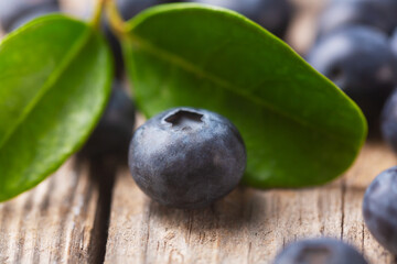 Blueberry berry close-up with leaves on wooden background