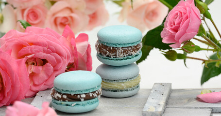 Obraz na płótnie Canvas stack of blue macarons on a white table and pink rosebuds, delicious dessert