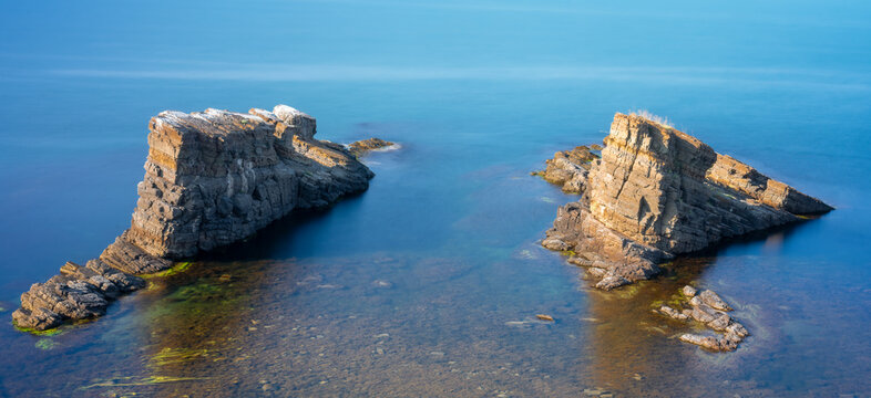 Aerial view of natural landmark The stone ships near Sinemorets, Bulgaria. Color landscape of rocks in calm blue sea water during a sunny day. Long exposure. Low shutter speed