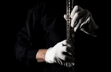 flutist in a black shirt, against a dark background .. male executor on a wooden wind instrument