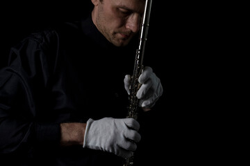 flutist in a black shirt, against a dark background .. male executor on a wooden wind instrument