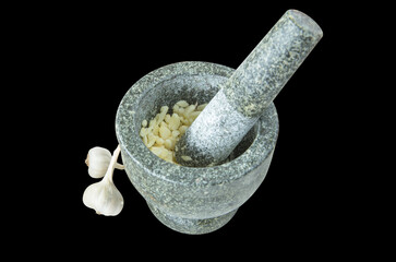 Top view of pound garlic in black stone mortar and pestle on black isolated.