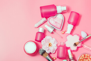 Obraz na płótnie Canvas Cosmetic products. Pink bottles and tubes with dispensers, rejuvenation capsules, heart-shaped blush, brushes, cream, essence. Top view