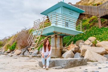 Cute young woman on a beautiful beach with a blue lifeboat in San Elijo State Beach, San Diego