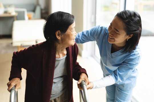 Asian female physiotherapist treating senior female patient at her home