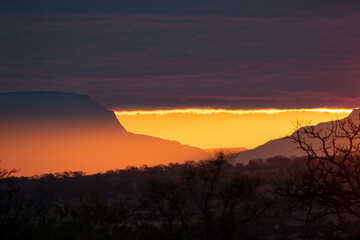 The horison at sunset, large mountains reveal golden light