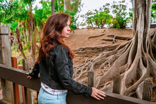 Beautiful woman walks through a rainforest with trees with huge roots in Balboa Park, san diego