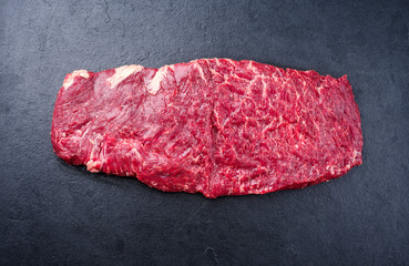 Raw wagyu skirt beef steak offered as top view on a black board