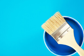 A paint brush is placed on a paint can. with blue background