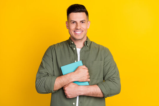 Portrait of attractive cheerful smart clever sporty guy hugging book note-pad isolated over bright yellow color background