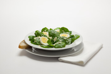 A healthy fresh spinach salad with almonds, hard boiled egg, feta, and a hard parmesan, romano style cheese