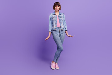 Fototapeta na wymiar Full size photo of young brunette lady stand wear spectacles jeans shirt isolated on purple background