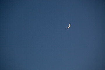 An idyllic view of the blue night sky with the waxing crescent moon. Clear sky before sunset