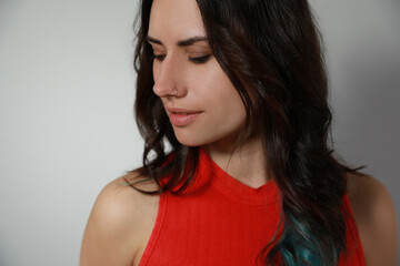 Young woman with nose piercing on grey background, closeup