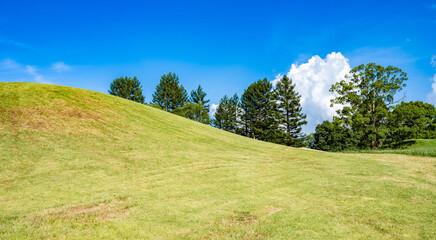 【夏】芝生が生えた丘の上に入道雲が立ち込める自然風景

