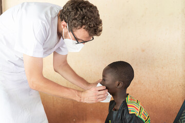 Compliant little African boy waiting for the doctor to fit his face mask