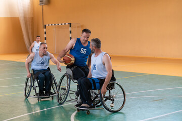 Fototapeta na wymiar Disabled War veterans mixed race opposing basketball teams in wheelchairs photographed in action while playing an important match in a modern hall. 