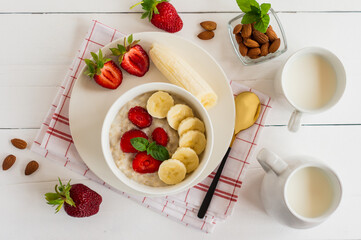 Breakfast. Oatmeal with bananas, strawberries, nuts on the wooden bakground. Healthy breakfast. Close-up. Top view