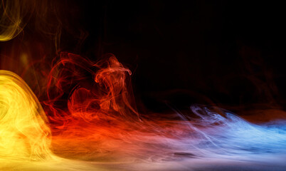 Art photo of colorful smoke moves on black background. Beautiful swirling colorful smoke.