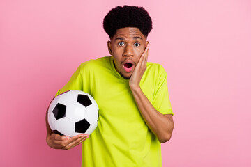 Photo of young african guy amazed shocked surprised hand touch cheek hold soccer ball goal isolated over pink color background