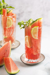 Two glasses with tall long drink with watermelon, lime slices - and mint