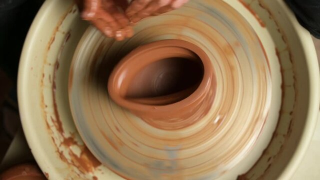 The craftsman makes a mistake in the production of a clay pot and spoils the shape, top view. The potter is angry because the painstaking work has been spoiled