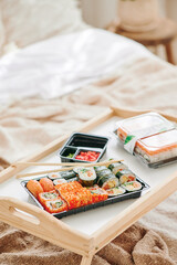 Classic Philadelphia sushi in plastic black container on bedside tray.Take away sushi food. High quality photo