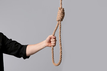 Man holding rope noose on light background, closeup