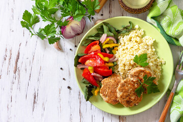 Healthy vegan food, keto or paleo diets. Homemade red fish cutlets with bulgur and fresh vegetable salad on a wooden table. Top view flat lay background. Copy space.