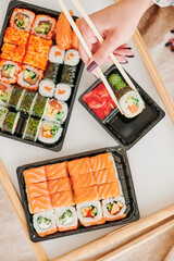 Young woman eating sushi at home. Home food delivery concept. Japan food. Top view. Space for text. High quality photo