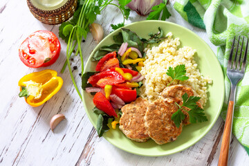 Healthy vegan food, keto or paleo diets. Homemade red fish cutlets with bulgur and fresh vegetable salad on a wooden table. Top view flat lay background.