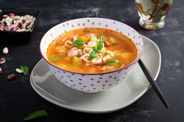 Minestrone, italian vegetable soup with pasta on dark table.
