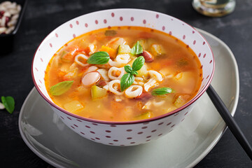 Minestrone, italian vegetable soup with pasta on dark table.