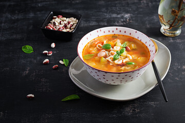 Minestrone, italian vegetable soup with pasta on dark table.