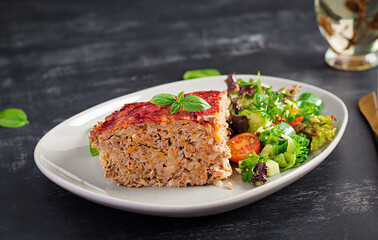 Slice of casserole with rice, minced beef meat and cabbage with tomatoes sauce on top decorated with basil on the plate