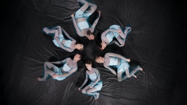 Rotating video of lying men and women with closed eyes in blue clothes