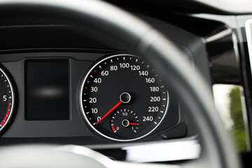 Speedometer on car dashboard, view through steering wheel