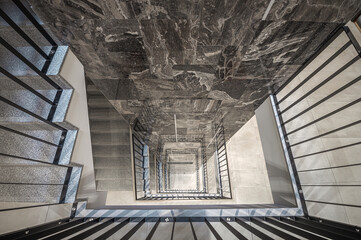 Obraz premium Staircase of modern apartment building. White walls with marble decorations. Metalic railings and tile floor. Clean look.