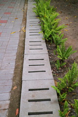 Ditch with concrete cover with holes on the side of the road