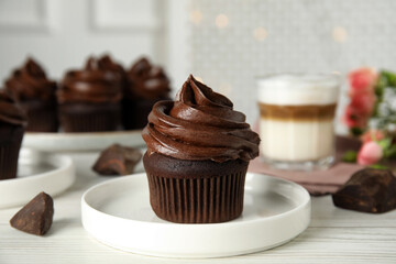 Plate with delicious chocolate cupcake on white wooden table