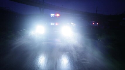 A black police car is driving fast at night with flashing lights.